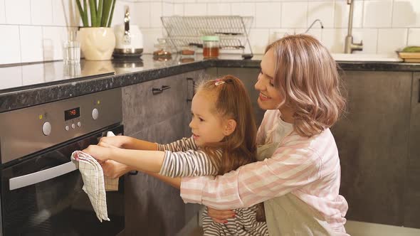 Cute Mother with a Little Daughter Bakes Cookies They Opened the Oven To Check the Readiness of