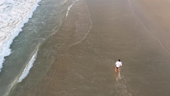 Aerial shot of young man running on the beach.