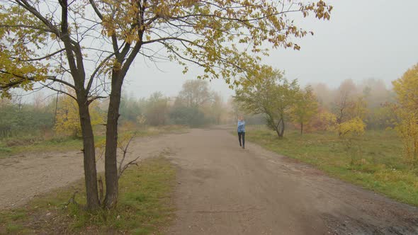 Woman Running in Park on Foggy Autumn Morning