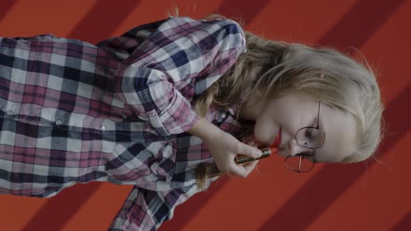 Girl Applying Lipstick While Looking at Smartphone