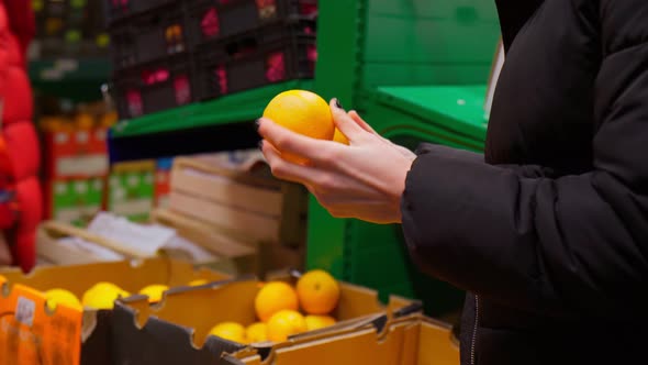 Woman Choice an Orange in Her Hand in a Supermarket