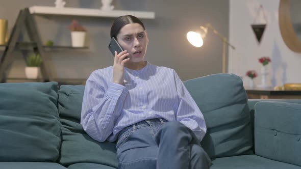 Angry Hispanic Woman Talking on Phone on Sofa