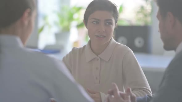 Indian Businesswoman Talking to Colleagues While sitting in Office