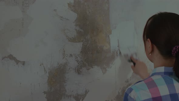 A Woman Puts Putty on the Walls While Making Repairs in Her House