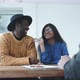 Happy multi ethnic couple holding keys to their new home sitting at a table with agent - VideoHive Item for Sale