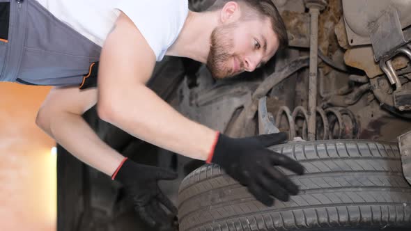 Vertical Video a Professional Car Mechanic Works Under the King of a Hoisting Machine in a Car