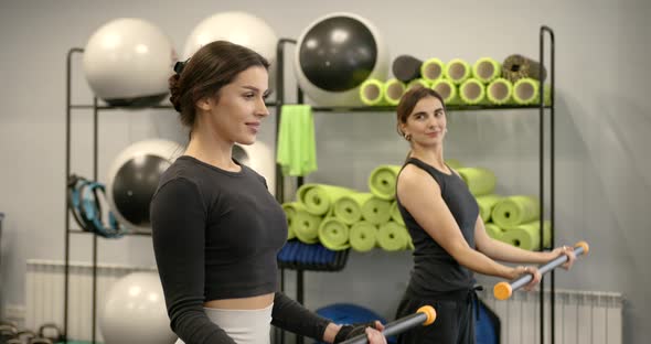 Two Attractive Darkhaired Women Perform Fitness Exercises with Equipment