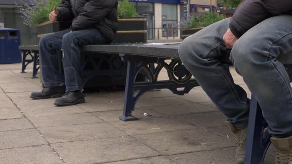 Two men sitting in town centre social distancing on bench