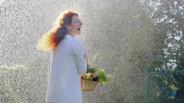 Woman Spinning in the Rain in the Garden with a Basket of Fresh Vegetables