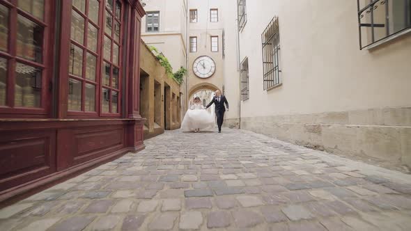 Newlyweds Running in the Center of the Old Town. Bride and Groom. Wedding