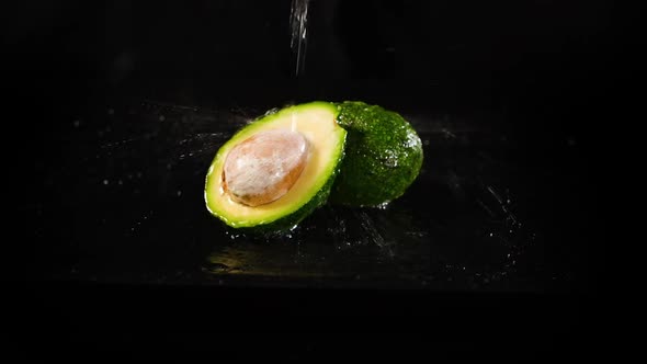 Watering Fresh Avocado By the Black Background