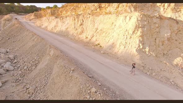 Beautiful Young Woman Walks Barefoot on a Sandy Road Among the Rocks and Stones