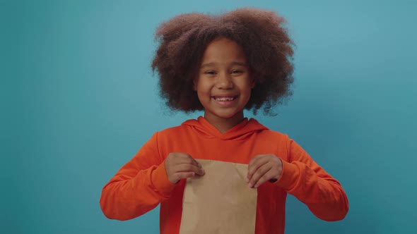 Smiling African American girl holding paper delivery bag looking at camera