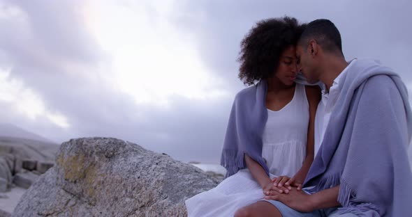 Couple wrapped in blanket on beach 4k