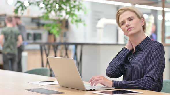 Tired Young Businesswoman with Laptop Having Neck Pain in Office 