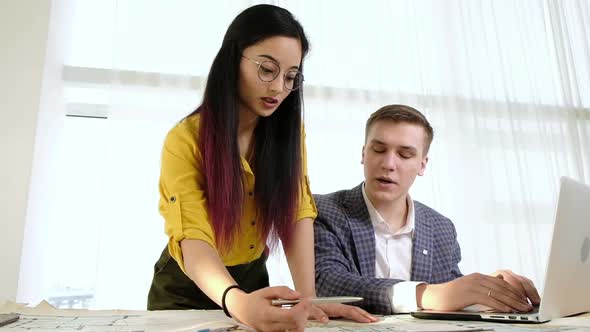 Young creative designers in bright office with large windows brainstorm.