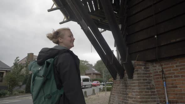 Slow motion footage of a female traveler observing the architecture underneath an old windmill in th