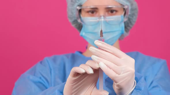 Professional Woman Doctor Holds a Syringe with a Vaccine on a Pink Background