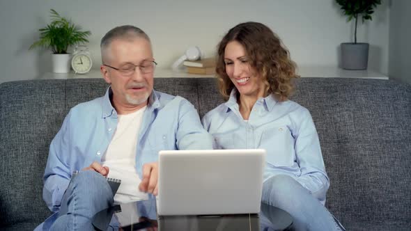 A Happy Middleaged Elderly Couple Makes Online Purchases on a Laptop