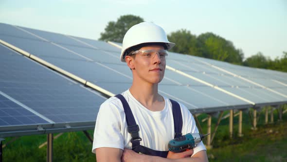 Engineer in a Special Equipment with Screwdriver is at the Solar Power Station alt