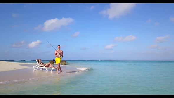 Family of two engaged on perfect lagoon beach wildlife by transparent lagoon and white sand backgrou