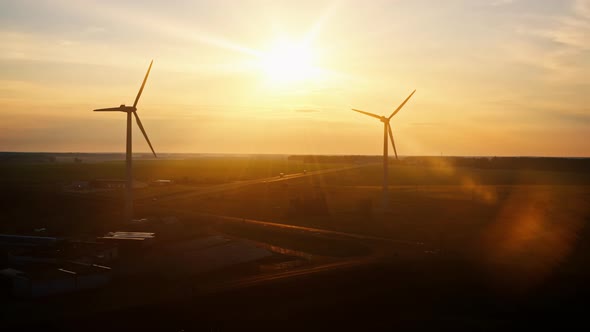 Aerial View Windmills Silhouettes Wind Turbines By Road in Field Backlit with Warm Sun Light During