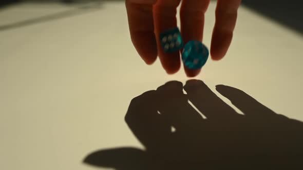 A Woman Throws Blue Cubes on a White Table