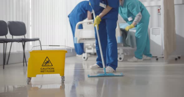 {Nurses Mopping Floor and Making Bed in Empty Hospital Ward