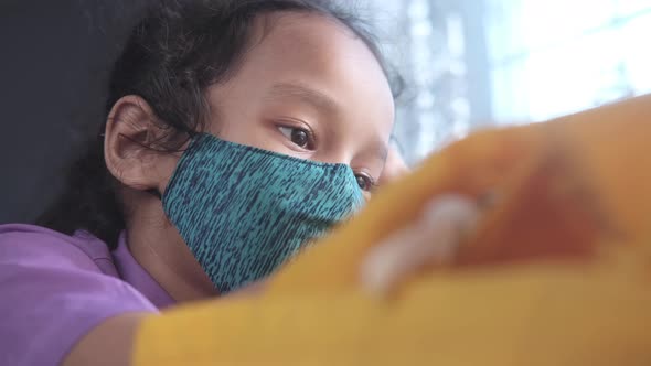 Happy Child Girl with Face Mask and School Dress Sitting on Chair