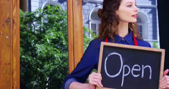 Smiling waitresses holding open sign board