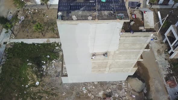 Concrete plaster finish applied to building side in Sam Son Vietnam as two construction workers swin