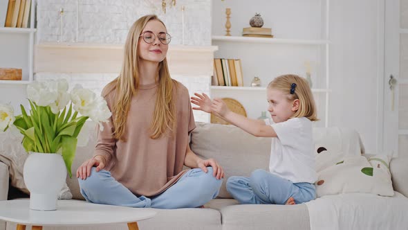 Calm Peaceful Caucasian Mother Young Woman Sitting on Sofa in Lotus Position Meditating Breathing