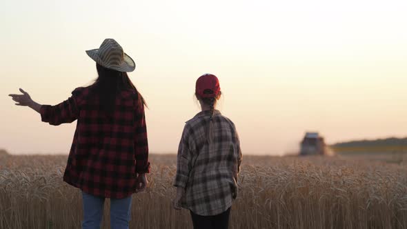 Young Mother Farmer Teaches Her Daughter to Work in a Wheat Field
