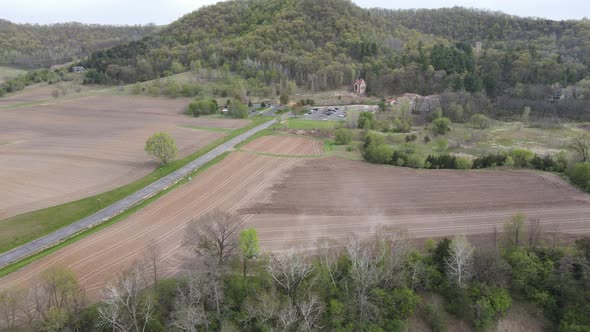 Rural midwest valley with plowed farm fields, road, creek, mountain and forest in distance.