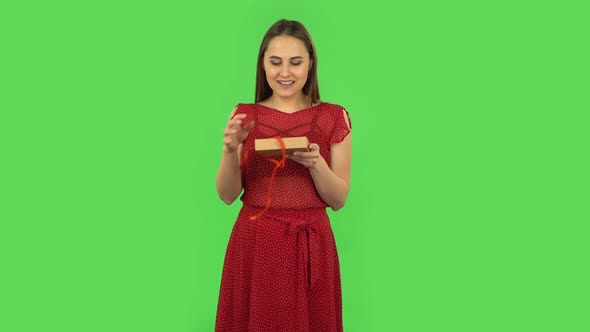 Tender Girl in Red Dress Is Opening the Gift, Very Surprised and Rejoicing. Green Screen