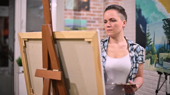 The artist works in her creative space, surrounded by paintings