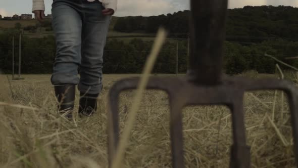 Farmer in field walking towards pitching fork