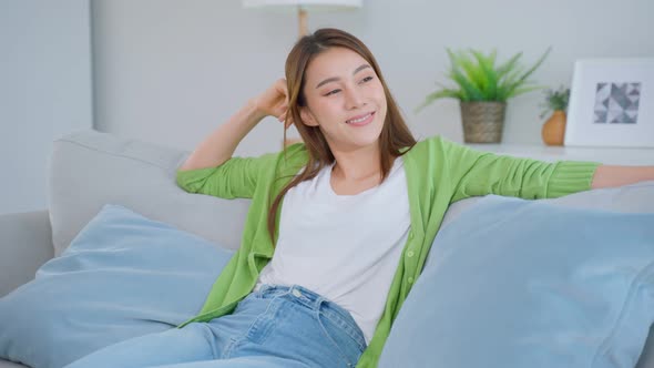 Asian beautiful woman jump into comfort sofa in living room spend leisure free time alone in house.