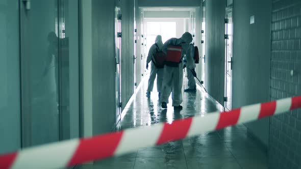 Disinfection, Sanitation Concept. Hallway Is Getting Disinfected By Workers in Hazmat Suits