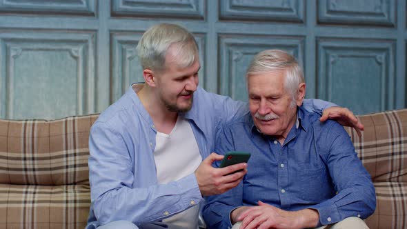 Happy Family Senior Father and Son Watching on Mobile Phone to Internet Online with Fun Together