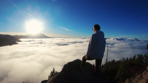 Woman Stands on the Top of the Mountain and Looks Into the Distance at Floating White Clouds