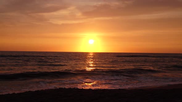 Sandy Beach with Choppy Waves of the Sea at Sunset