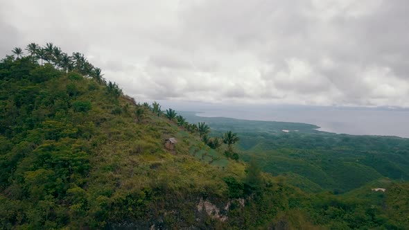 Beautiful aerial shot flying towards a mountain covered in trees with a huge breathtaking landscape