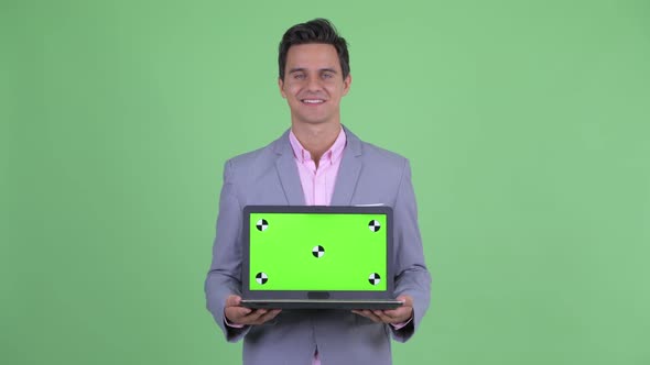 Happy Young Handsome Businessman Thinking While Showing Laptop