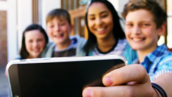 Smiling schoolkids taking selfie with mobile phone