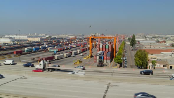 Aerial of vehicle driving on highway and shipping yard in background