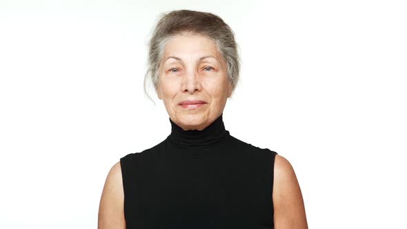 Slow Motion Portrait of Adult Kind Woman with White Tied Hair Looking at Camera Smiling Nodding