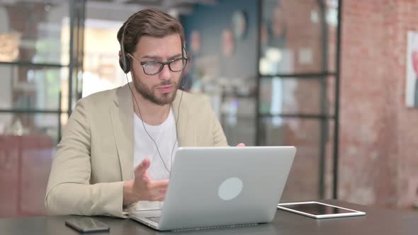 Man Talking on Headset Working on Laptop