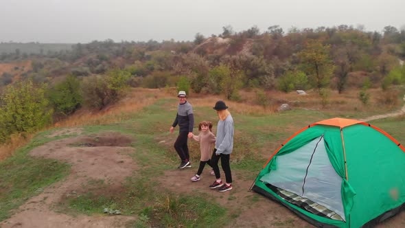 Aerial View of Young Family Parents and Child Walk Near Camping Tent While Hiking Together in Spring