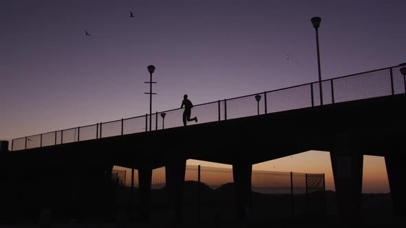 Silhouette of man running on bridge in the evening